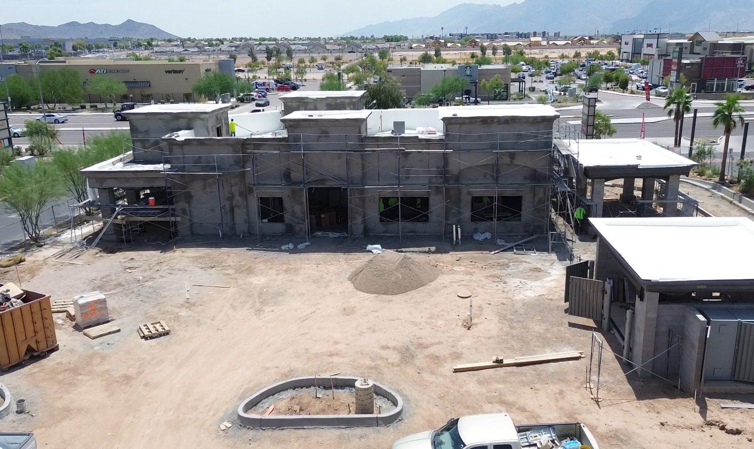 Aerial view of a retail building shell under construction, with mountains beyond