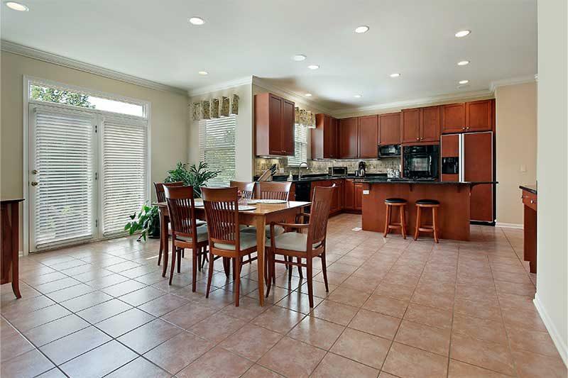 A kitchen with cherry cabinets, a tiled floor and a dining table by sliding doors