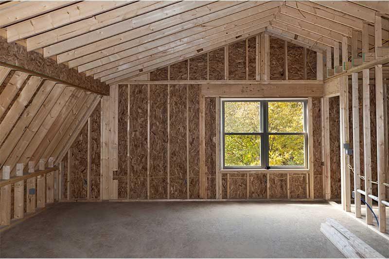 The timber frame of a room addition, with a new window and exposed rafters