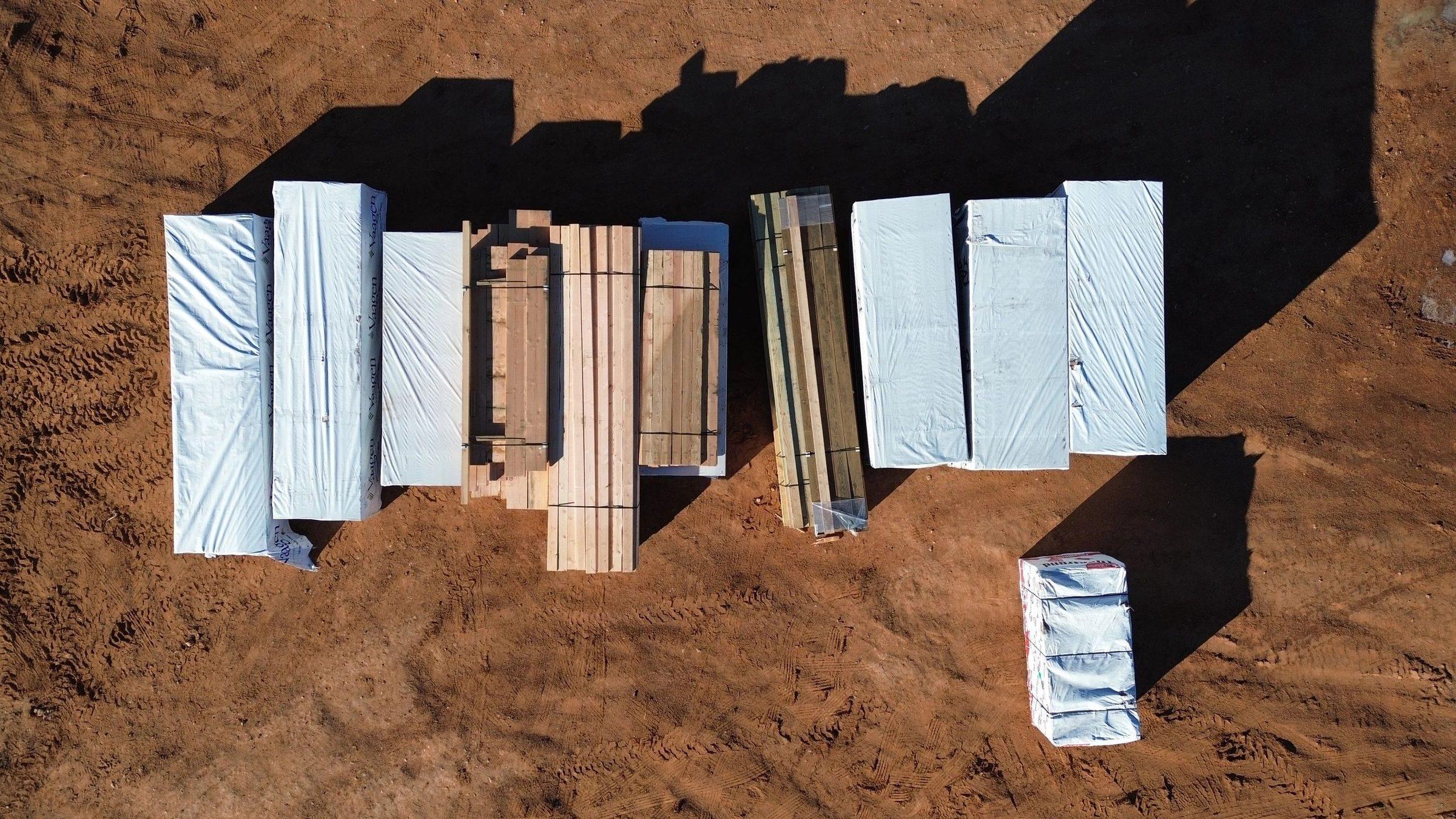 Aerial view of a school campus site in early construction, with materials staged on red desert soil