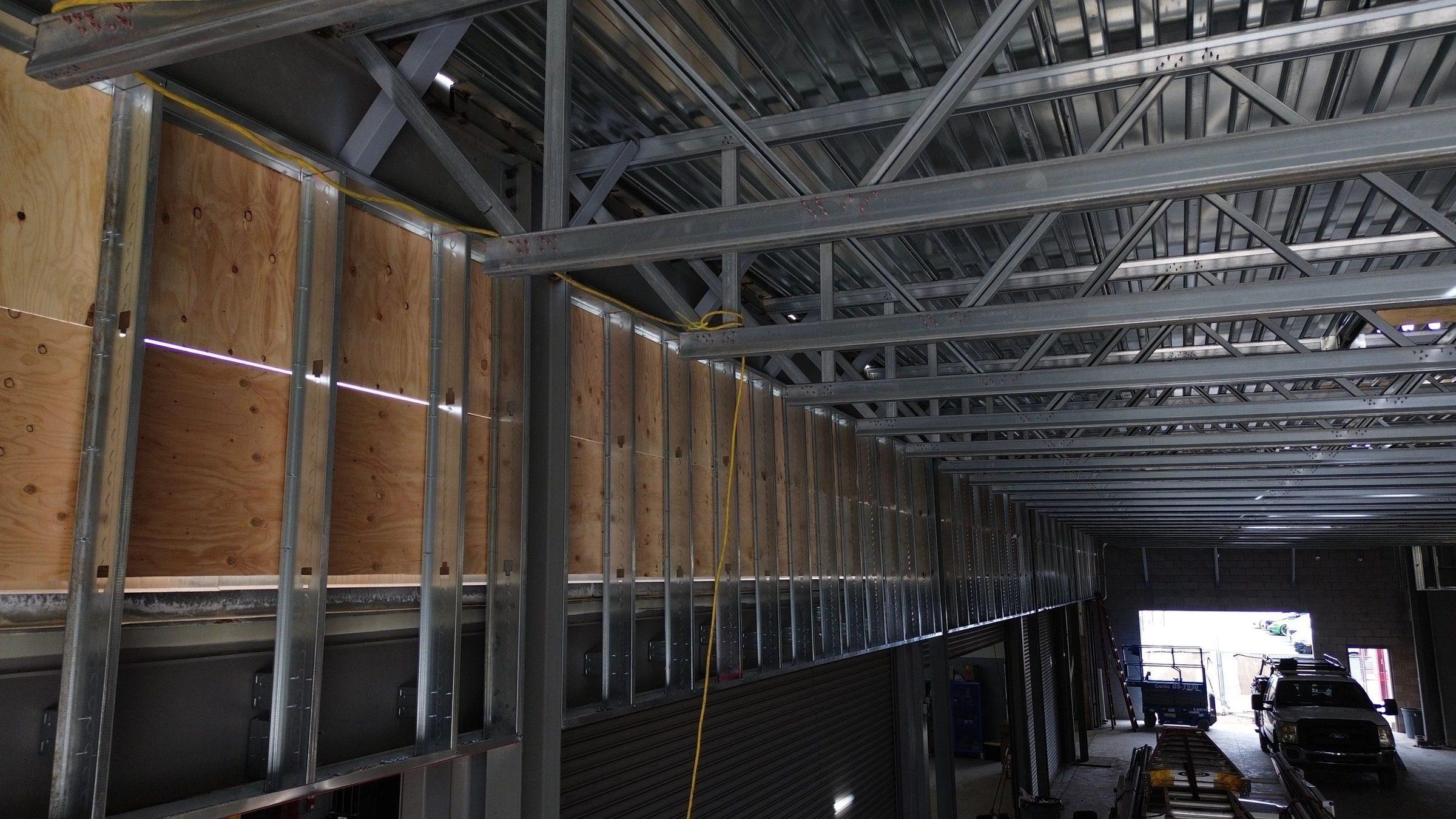 Metal-stud framing along the inside wall of a dealership building under construction