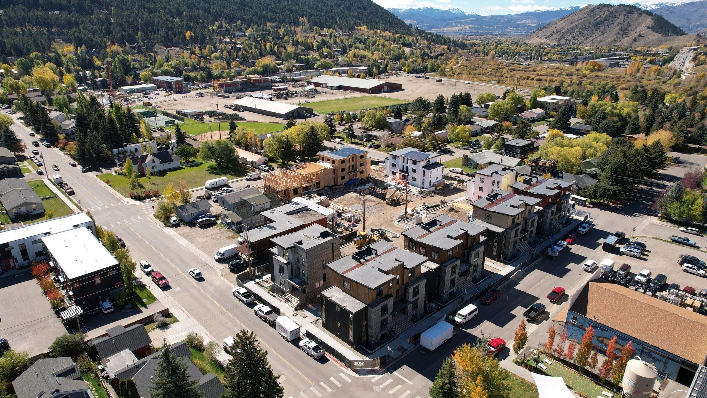 Aerial view of apartment buildings along a town street in autumn, with mountains beyond
