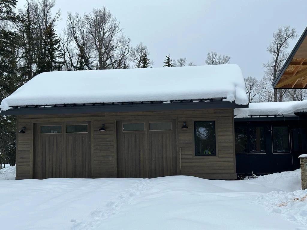 The garage wing of a mountain home with timber siding, in snow